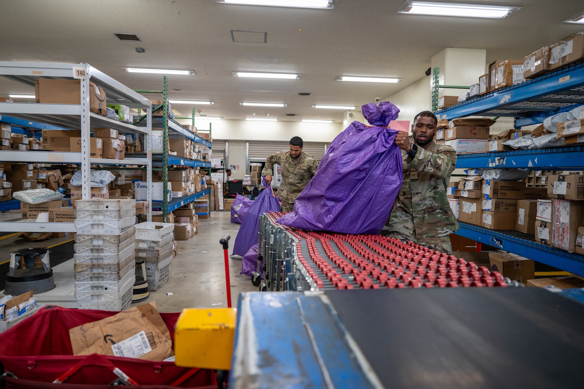 Service members put bag of parcels onto conveyor belt.