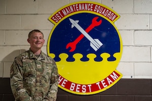 U.S. Air Force Staff Sgt. Bryce Vincent, 51st Maintenance Squadron corrosion control lead, poses next to his shop’s emblem at Osan Air Base, Republic of Korea, July 31, 2025.