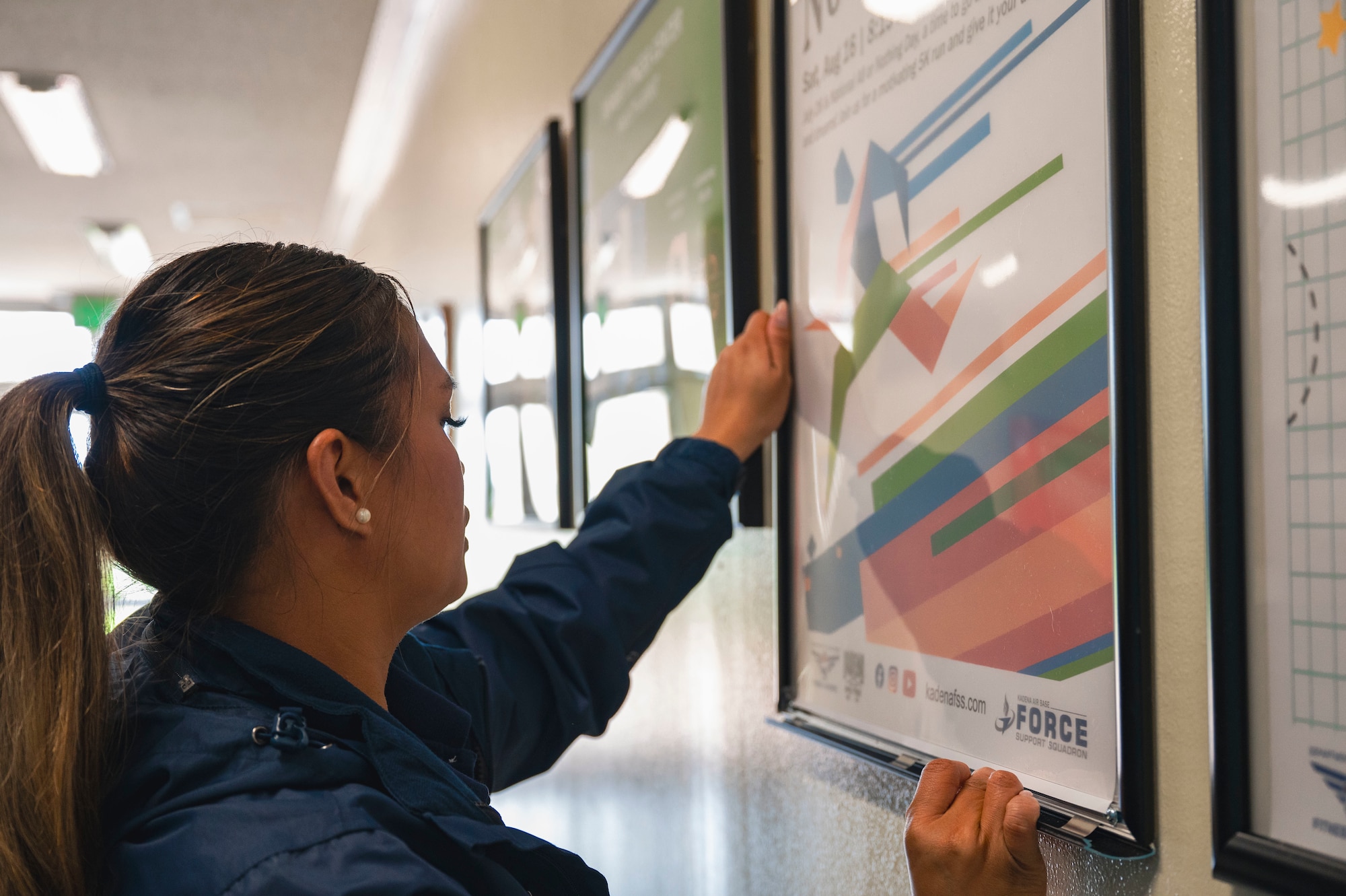 U.S. Air Force Staff Sgt. Keith Cruz, 18th Force Support Squadron programs and events manager, hangs a sign at the Risner Fitness Center on Kadena Air Base, Japan, July 30, 2025.