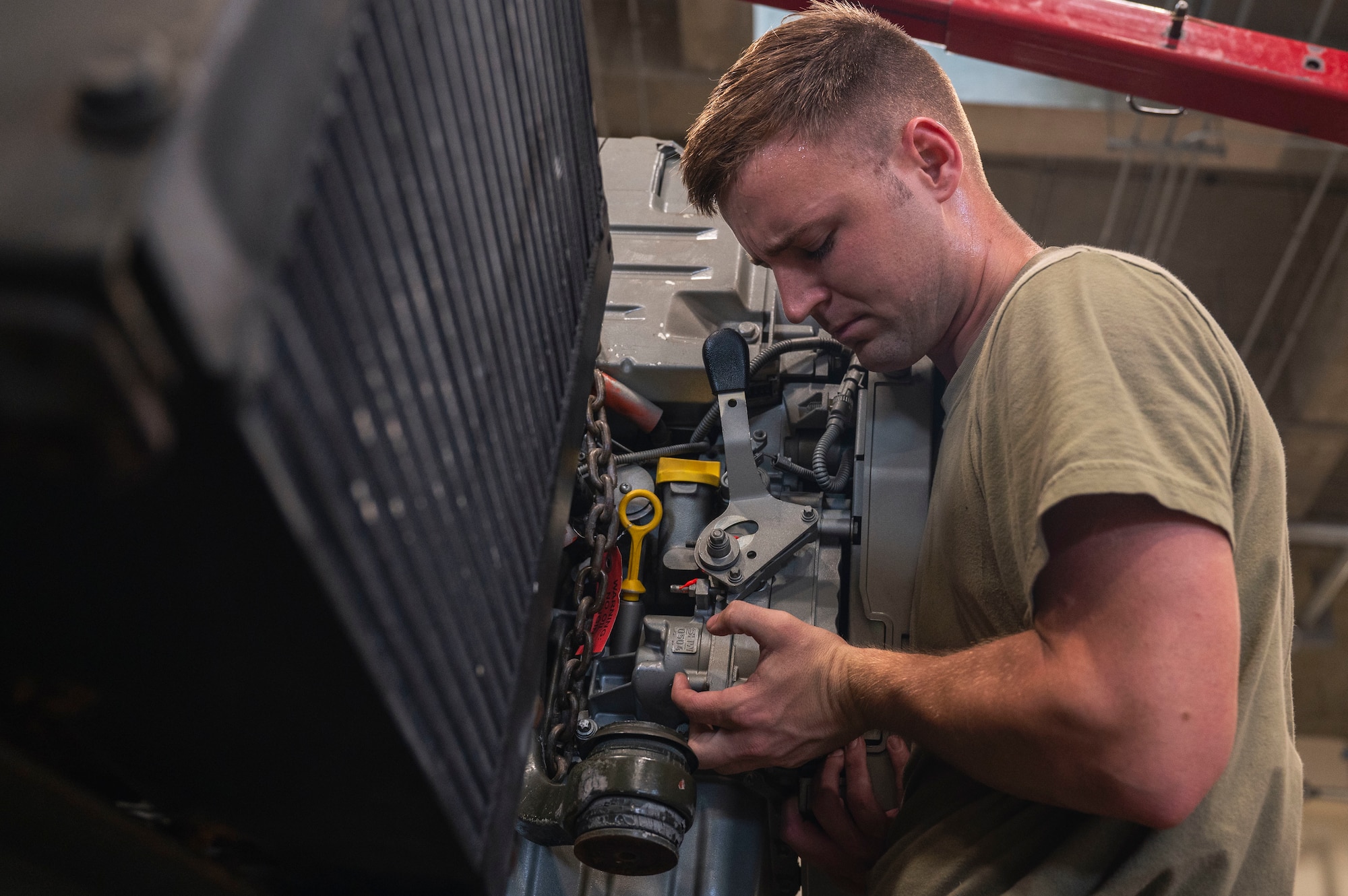 U.S. Air Force Staff Sgt. James Kreps, 18th Logistics Readiness Squadron vehicle maintenance special purpose non-commissioned officer, lifts an engine into place at Kadena Air Base, Japan, July 30, 2025.