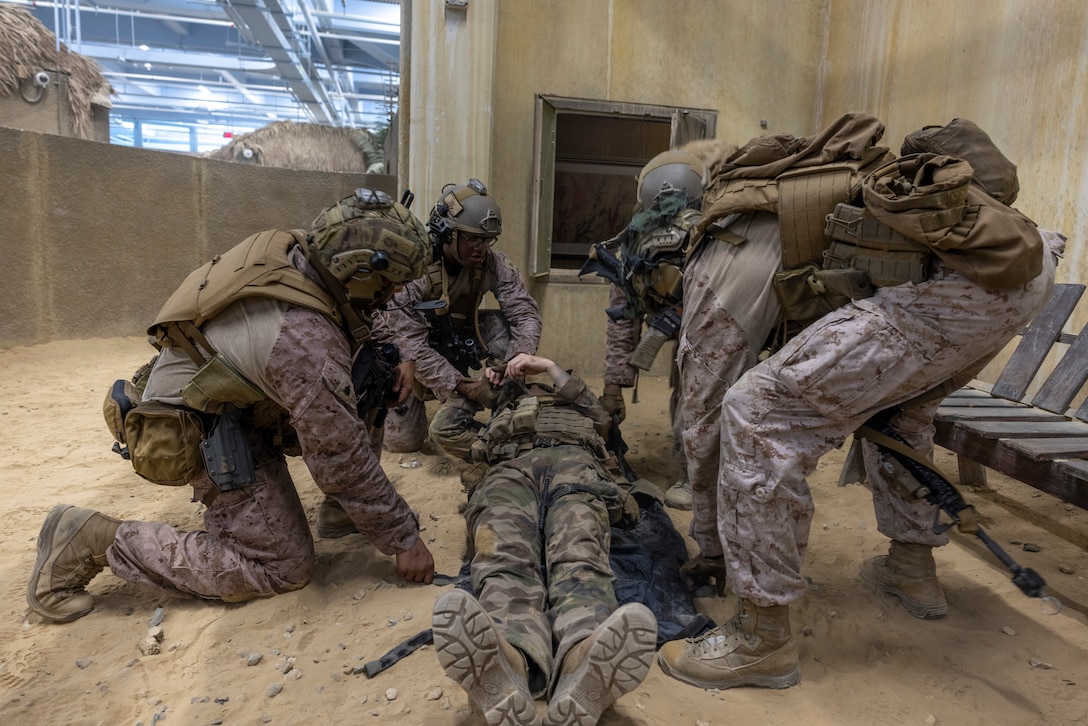 U.S. Marines with 2nd Air Naval Gunfire Liaison Company, II Marine Expeditionary Force Information Group, prepare to extract a simulated wounded French Marine with 3rd Marine Artillery Regiment from the Infantry Immersion Trainer during exercise Burmese Chase 25 at Marine Corps Base Camp Lejeune, North Carolina, July 30, 2025. Burmese Chase is an annual U.S. led, multi-lateral training exercise comprised of integrating ground and air fires, infantry tactics and naval gunfire alongside NATO allies to enhance combat readiness and interoperability. (U.S. Marine Corps photo by LCpl. Payton Walley) (This photo has been altered for security purposes by blurring out faces.)