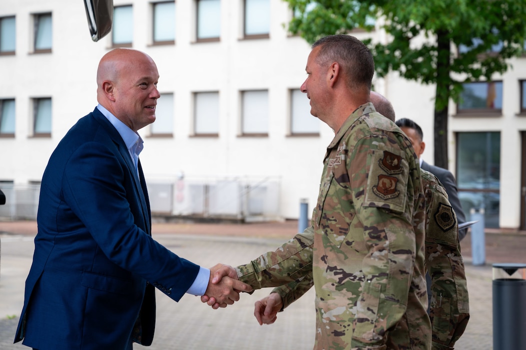 Two men shake hands outside a bus