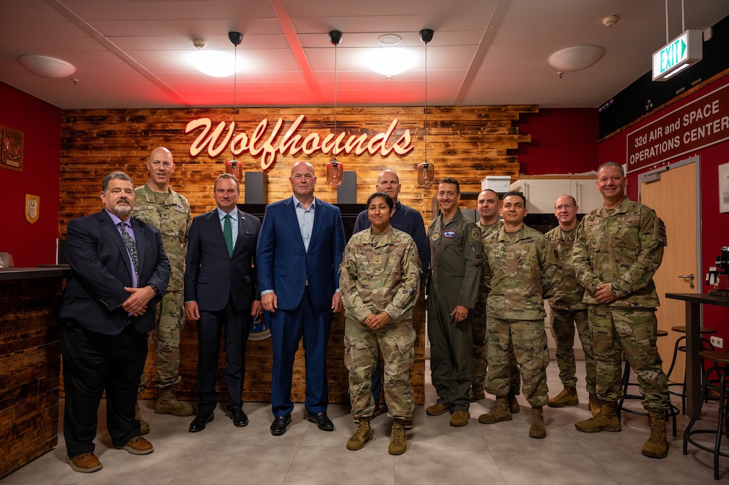 A group stands in front of a "Wolfhounds" sign in the heritage room