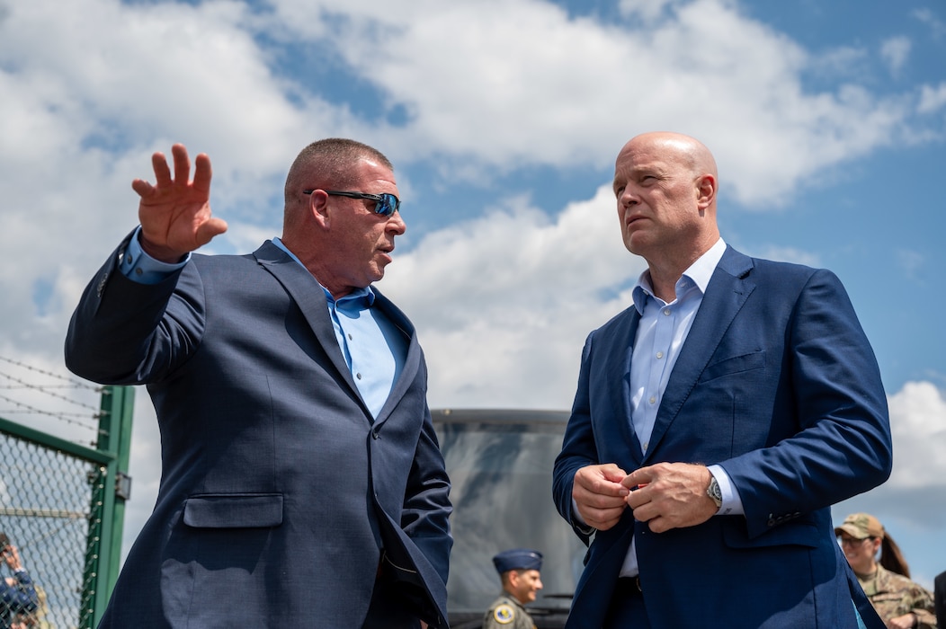 Two men talk looking very focused with a blue sky in the background