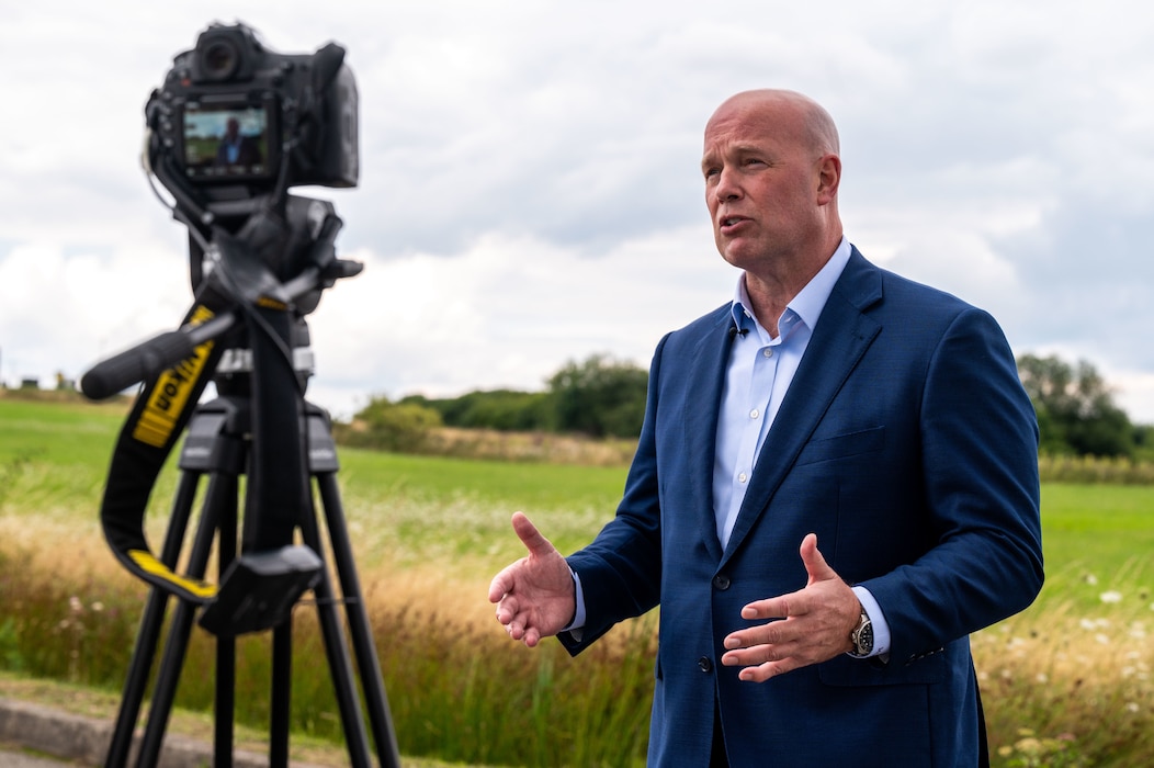 man stands by a camera talking