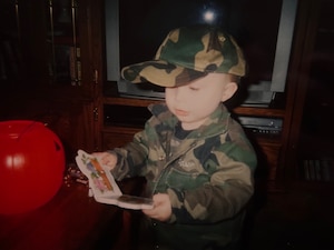 A young boy wears a military style camo outfit.