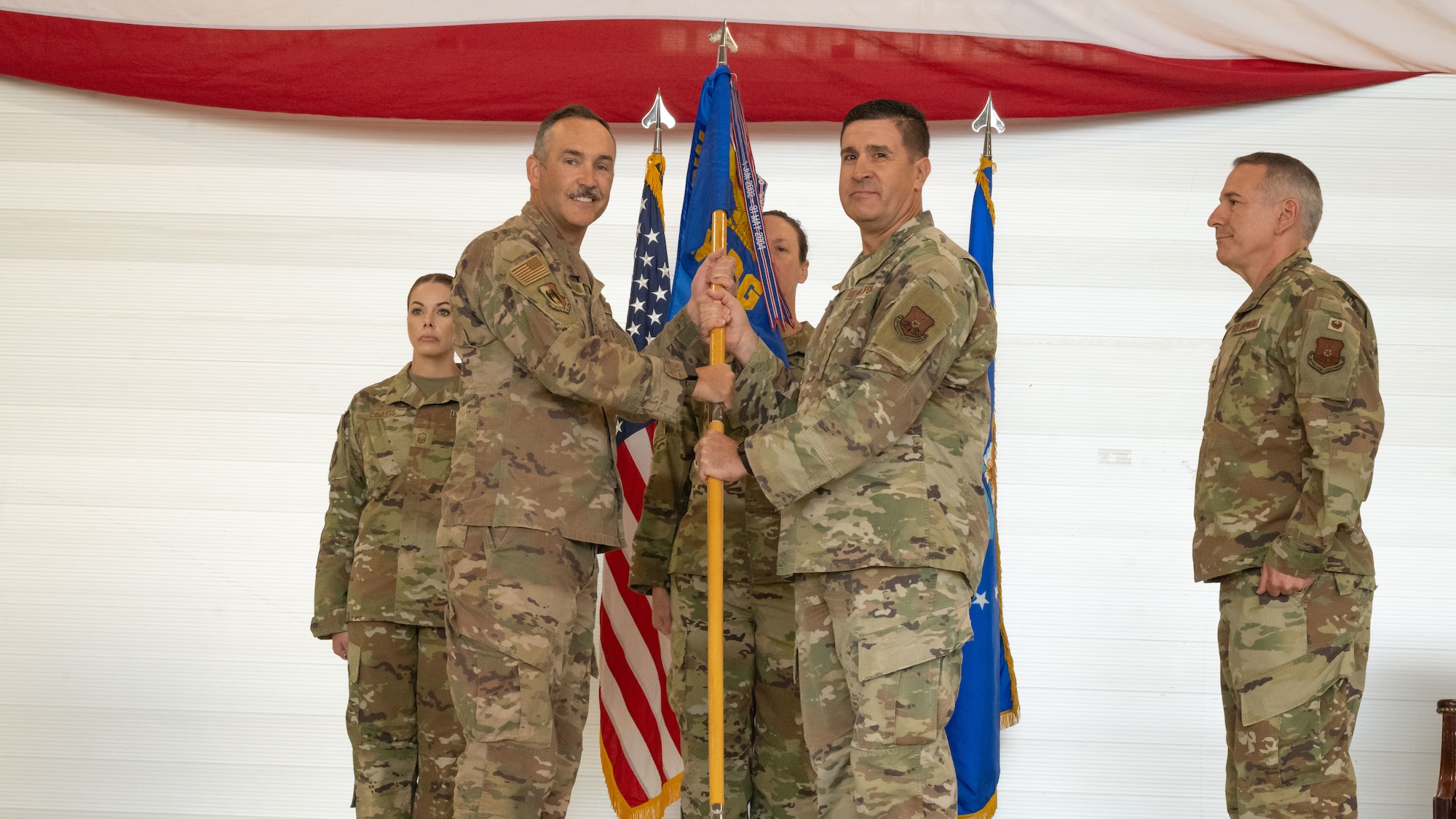 U.S. Air Force Col. Shaun Westphal, 5th Medical Group (5MDG) commander, presents the guidon to U.S. Air Force Col. Jesse Lamarand, 5th Bomb Wing commander, during the 5MDG change of command ceremony at Minot Air Force Base, North Dakota, July 31, 2025. The passing of the guidon to Lamarand represents the transition of power to the next commander.