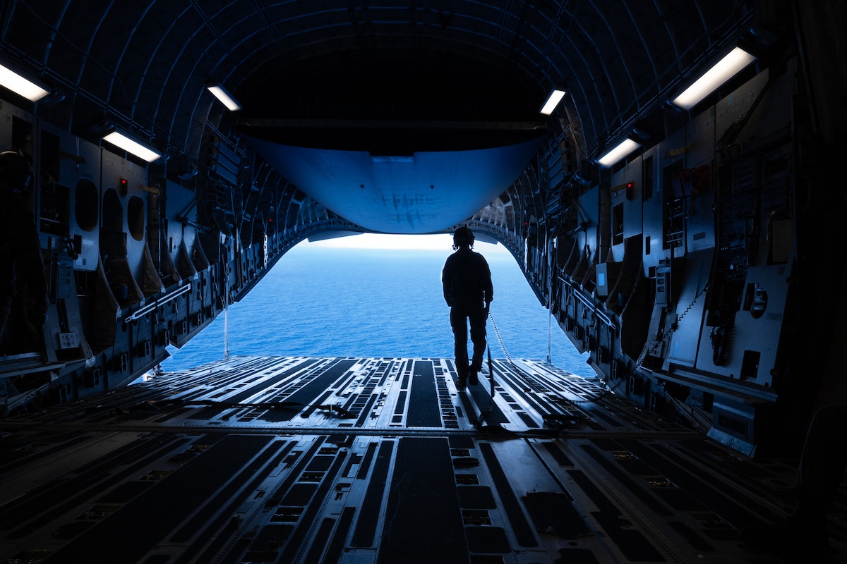 U.S. Air Force Senior Airman Dylan Weil, 16th Airlift Squadron loadmaster, looks out over the water from a C-17 Globemaster III during cargo airdrop proficiency training over the U.S. Indo-Pacific Command area of responsibility in support of Talisman Sabre 2025, July 25, 2025. Talisman Sabre is the largest bilateral military exercise between Australia and the United States, aimed at strengthening relationships and interoperability among key allies and partners to promote a safe and secure Indo-Pacific. The exercise also enhances collective capabilities to respond to a wide range of potential security concerns. (U.S. Air Force photo by Tech. Sgt. Eric Summers Jr.)