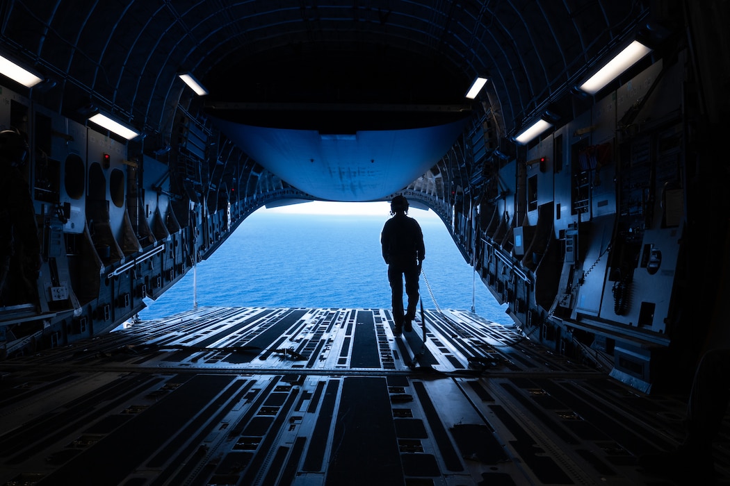 Senior Airman looks out over the water from a C-17 Globemaster III