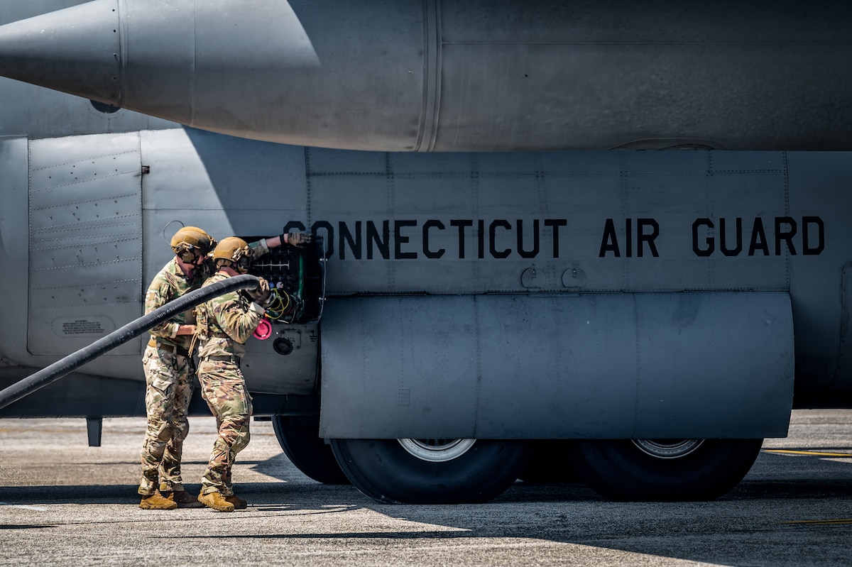 Air National Guard Tech. Sgt. Jose Hernandez, 103rd Logistics Readiness Squadron forward arming and refueling point operator, shows Air National Guard Tech. Sgt. Kyle Leven, an Airman assigned to the 104th Logistics Readiness Squadron, how to attach a refueling hose to a C-130 during a Distributed Integrated Combat Turn exercise at Westover Air Reserve Base, Mass., July 24, 2025. Leven is training to become hose deployed personnel and will complete his certification in September. (U.S. Air National Guard photo by Timothy Koster)