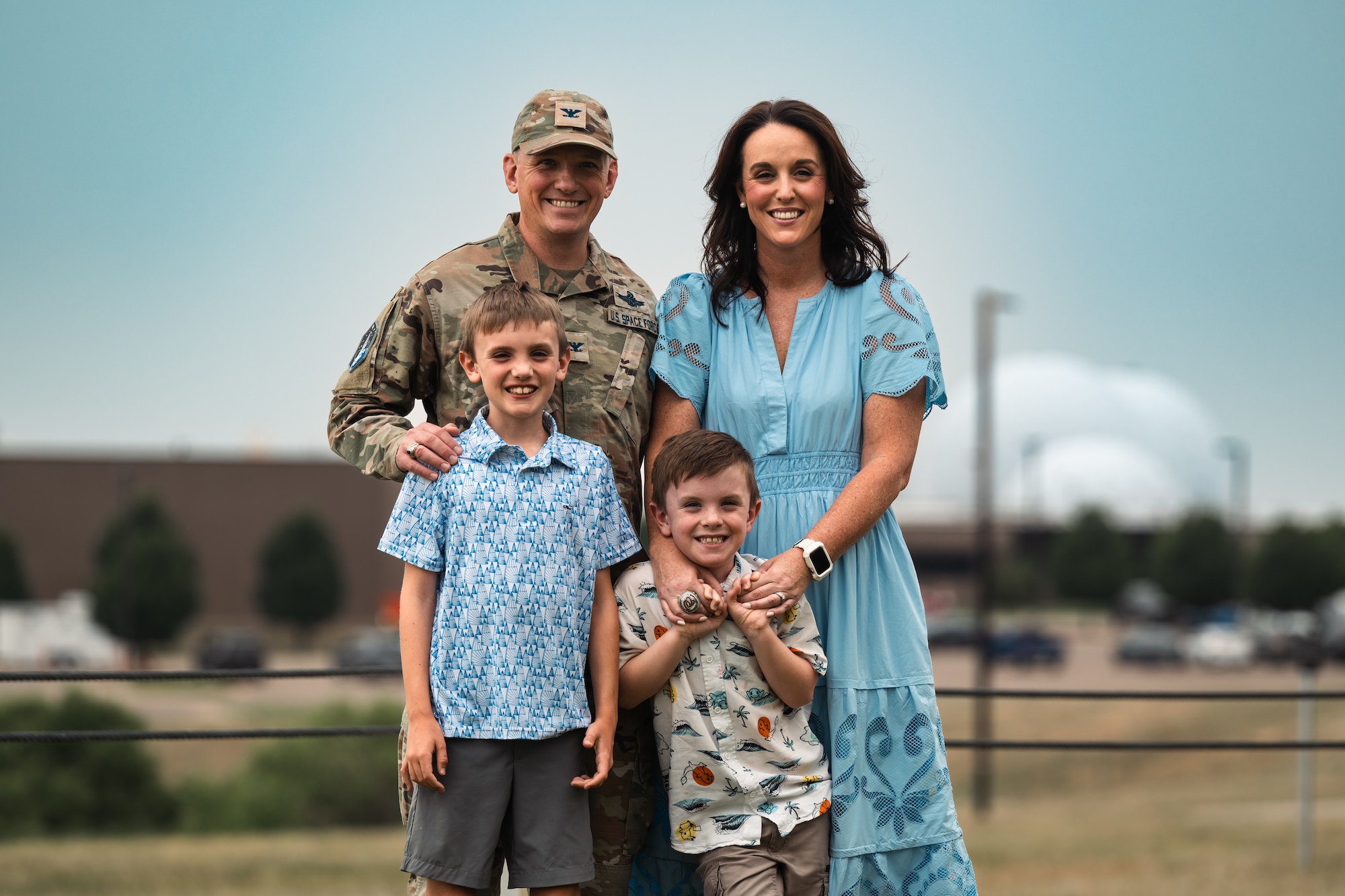 Uniformed man stands with woman and two young boys