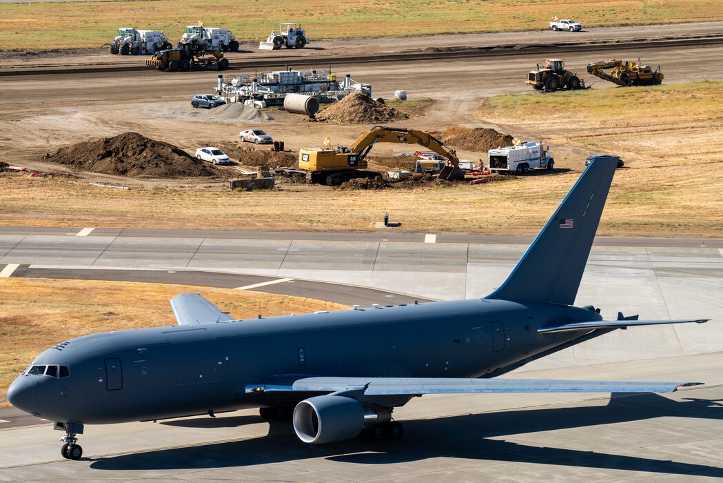 View from air traffic control tower of construction crew working on flight line as a KC-46 crosses an adjacent runway