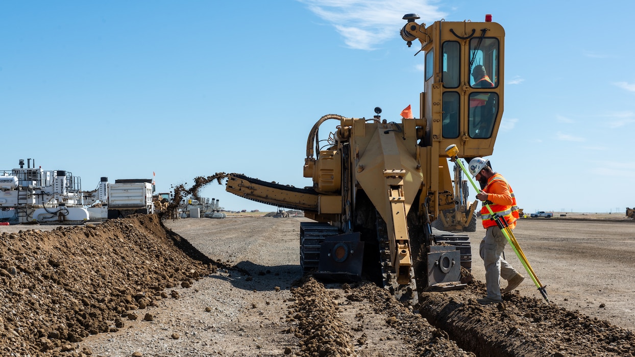 Construction crew working on flight line with a trencher