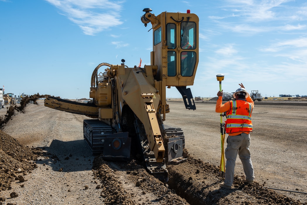 Construction crew working on flight line with a trencher