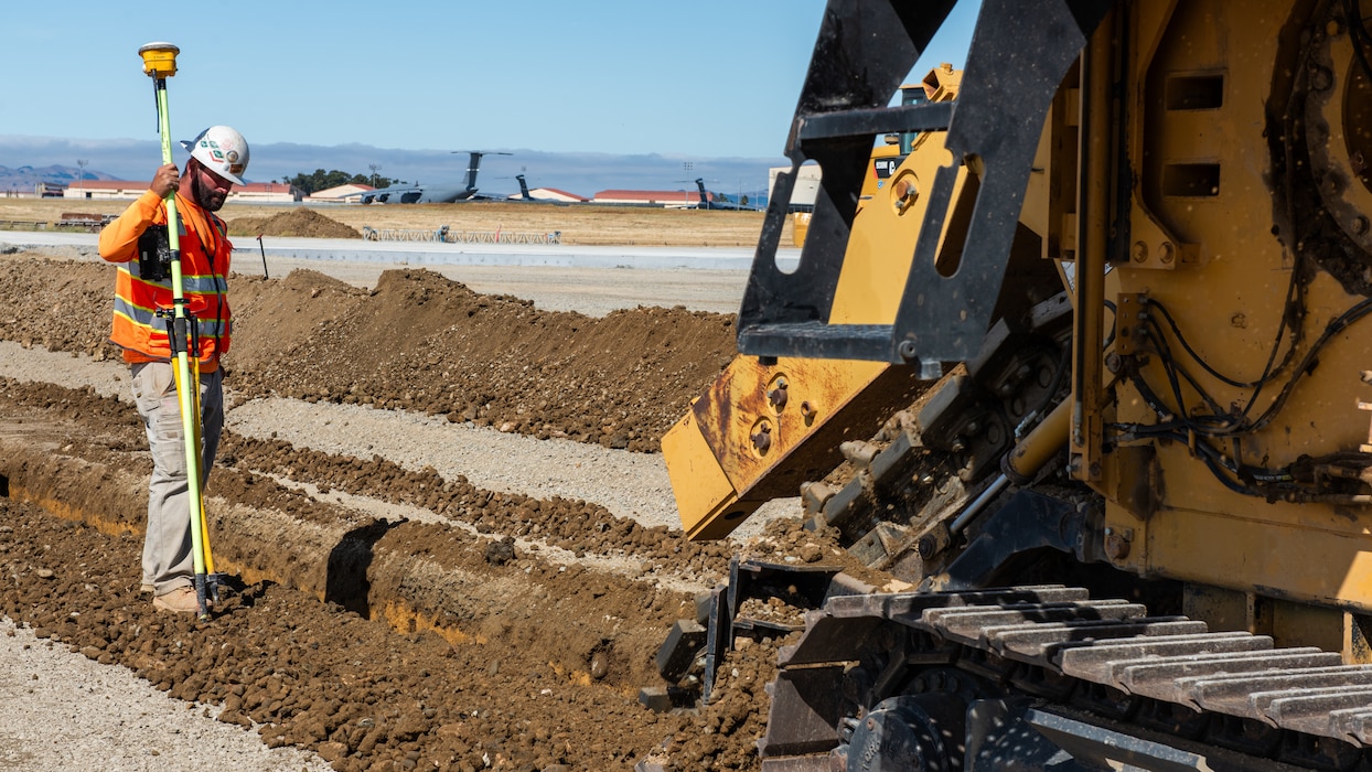 Construction crew working on flight line with a trencher