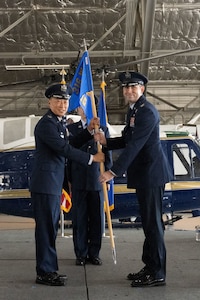 U.S. Air Force Col. Jun S. Oh, 316th Wing and installation commander, presents the guidon to U.S. Air Force Col. Kevin Geoffroy, incoming 316th Operations Group commander, during the change of command ceremony at Joint Base Andrews, Md., July 31, 2025.