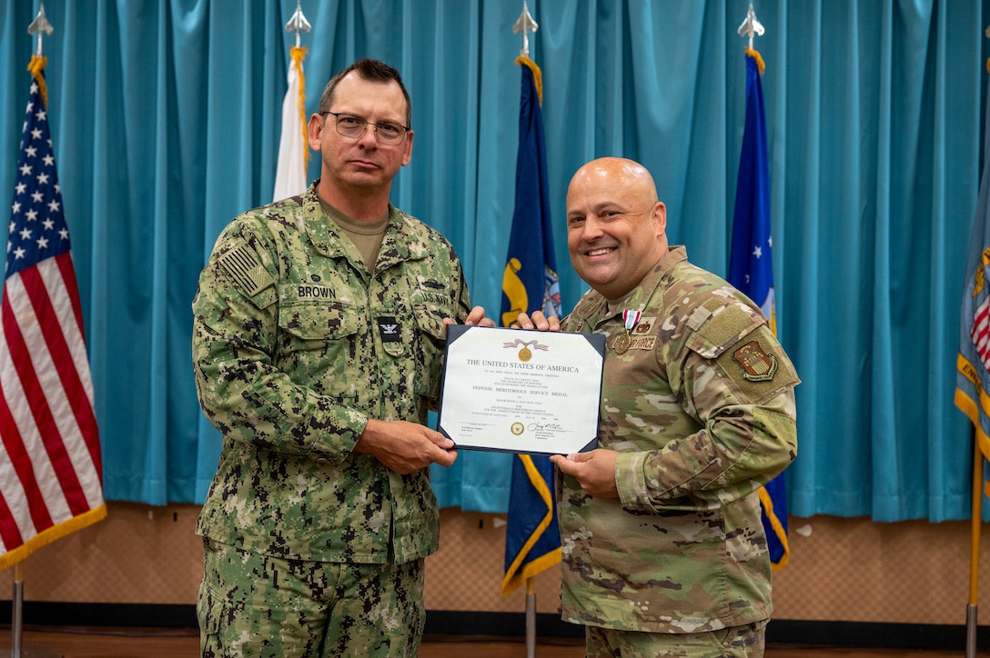 Two men display an award.