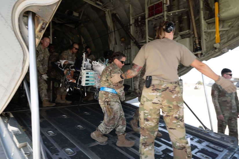 Troops remove patients from a ramp in back of an airplane.