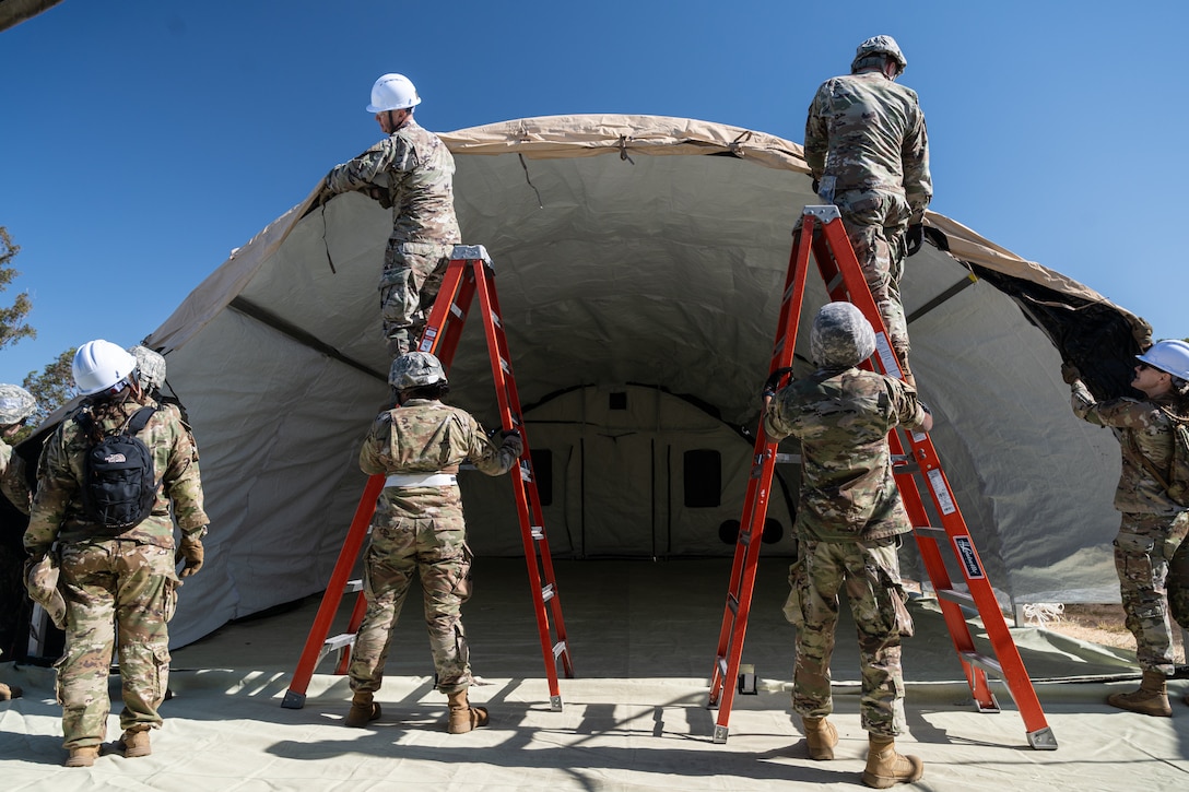 Airmen secure a tarp for an En Route Patient Staging System