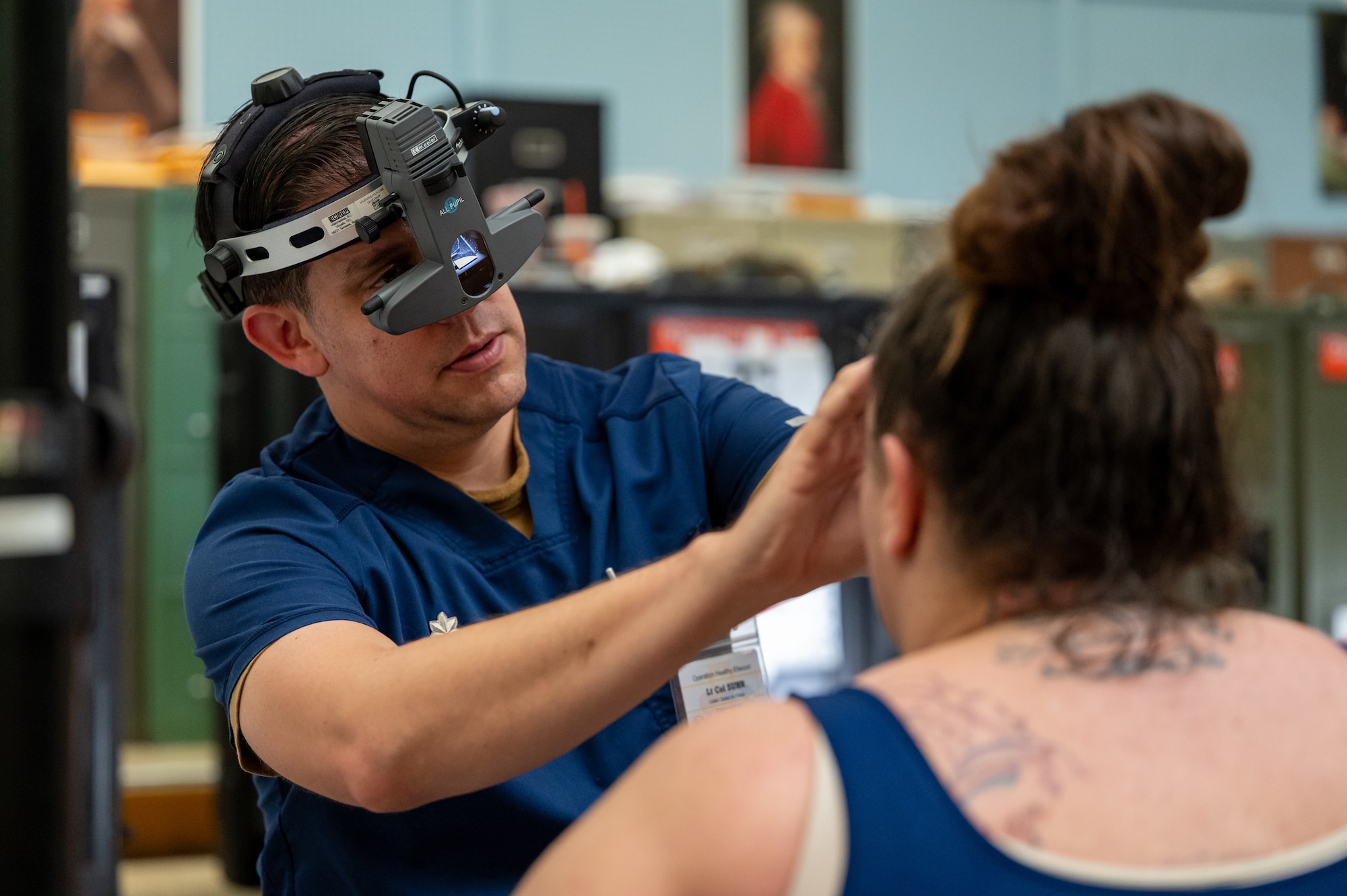 A man wears a binocular indirect ophthalmoscope while conduct an eye exam on a patient.
