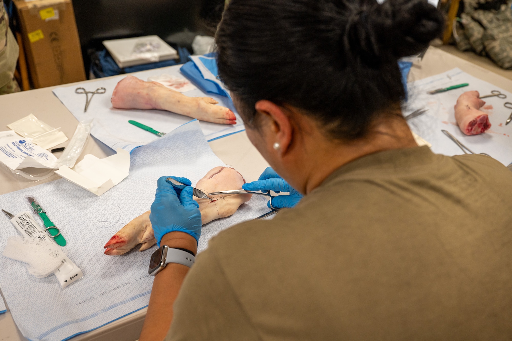 A woman conducts suture on a pig's leg in a classroom.