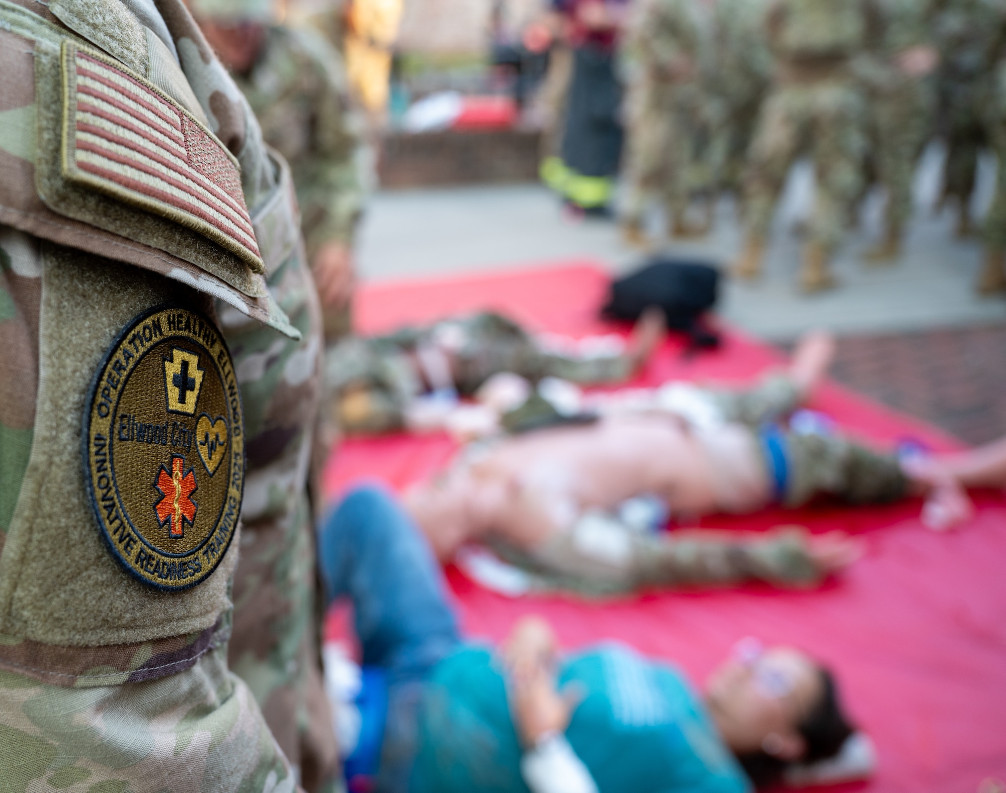 A uniform patch that reads "OPERATION HEALTHY ELLWOOD INNOVATIVE READINESS TRAINING" rests on a uniform below an American flag patch.