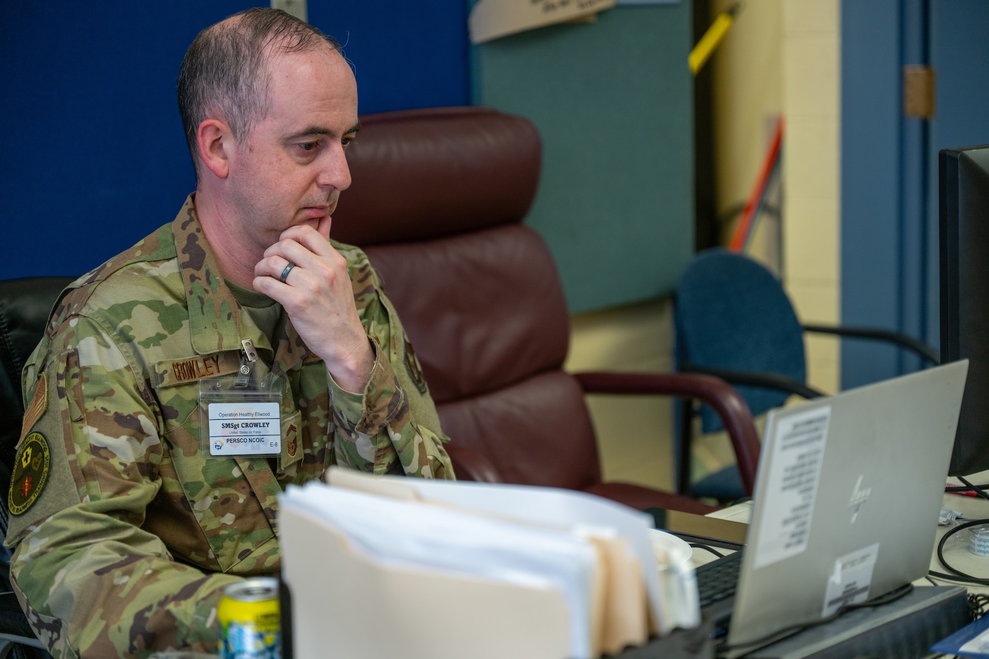 A man ponders while looking at a computer screen.