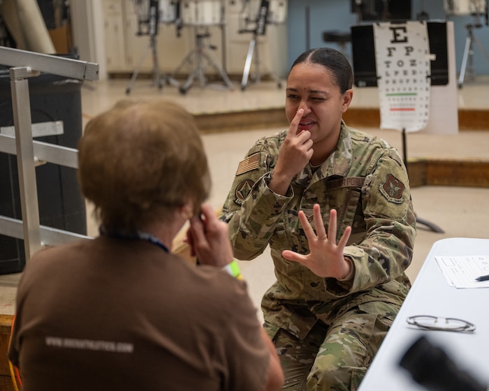 A woman in uniform conducts a vision exam for a civilian.