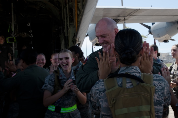 Civil Air Patrol cadets high-five a pilot outside of a static display of a C-130J.