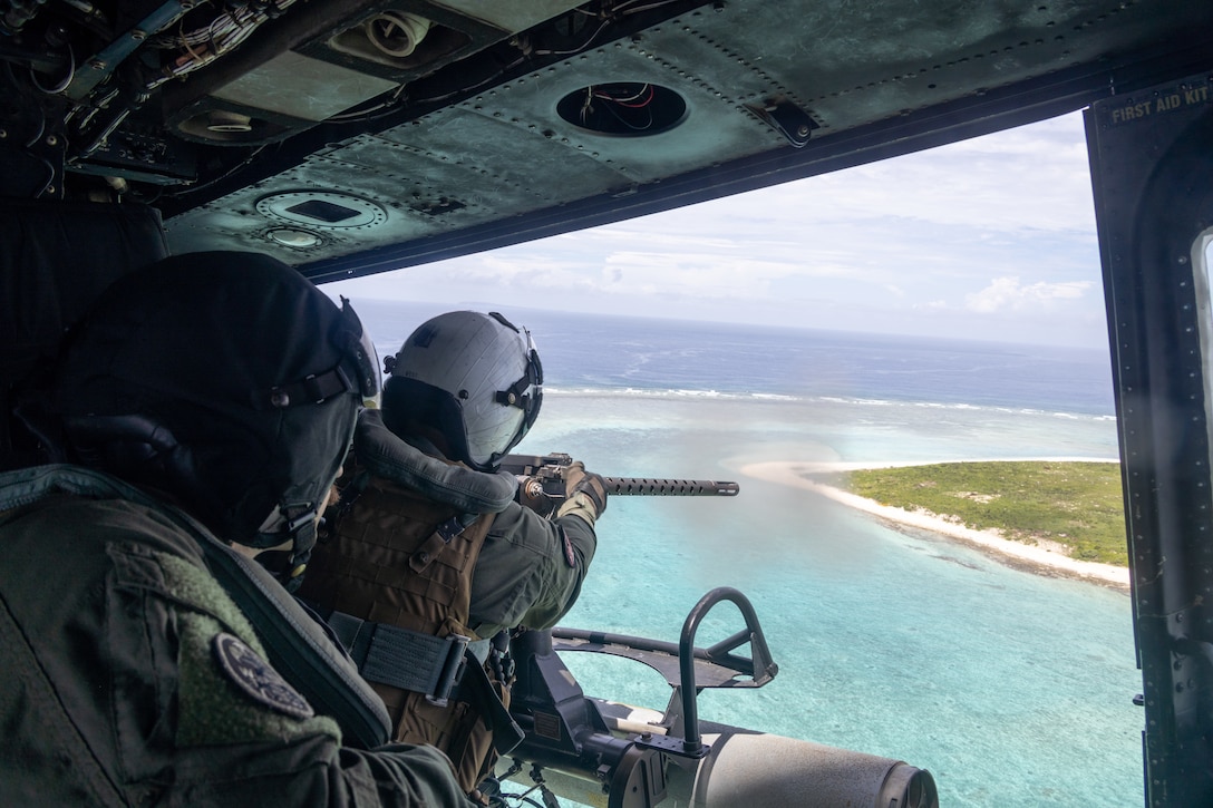 U.S. Marine Corps Sgt. Ethan Cox, right, a UH-1Y Venom crew chief with Marine Light Attack Helicopter 169, Marine Aircraft Group 36, 1st Marine Aircraft Wing, fires a GAU-21 machine gun during a live fire exercise on W174 training area, Okinawa, Japan, July 31, 2025.