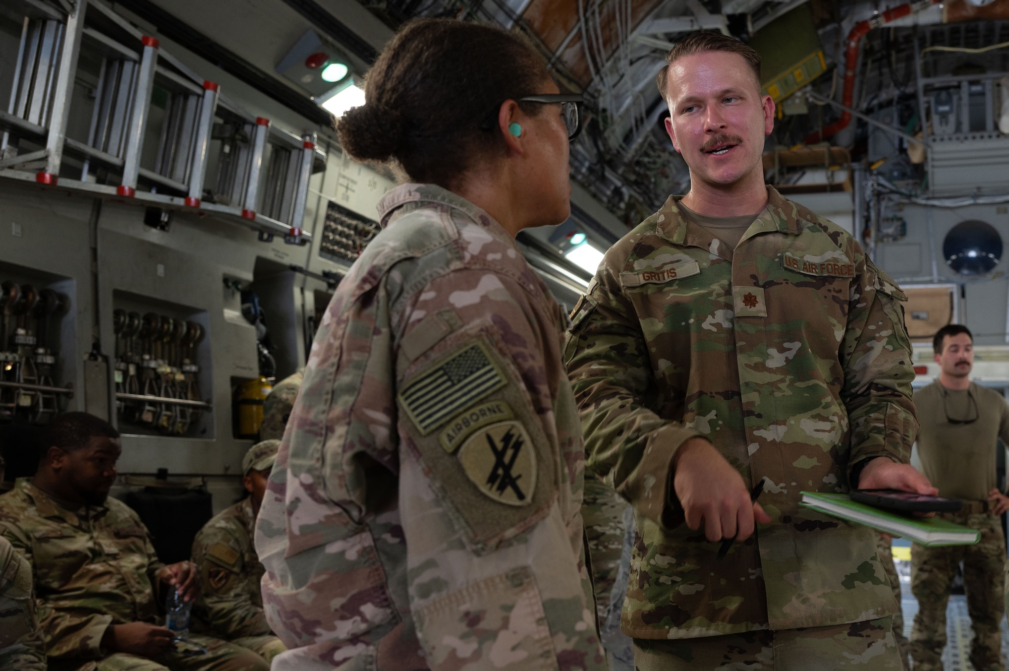 U.S. Air Force Maj. Matthew Gritis, 379th Expeditionary Medical Squadron nurse anesthesiologist, talks with U.S. Army Staff Sgt. Ebony O’Brien, 3rd Medical Battalion,147th Medical Detachment Veterinary Services animal care specialist, during military working dog training within the U.S. Central Command area of responsibility, July 22, 2025. The Army Veterinary Corps partnered with the 379th Expeditionary Security Forces Squadron to provide medical personnel hands-on training in aeromedical evacuation procedures involving MWDs. (U.S. Air Force photo by Senior Airman Dieondiere Jefferies)