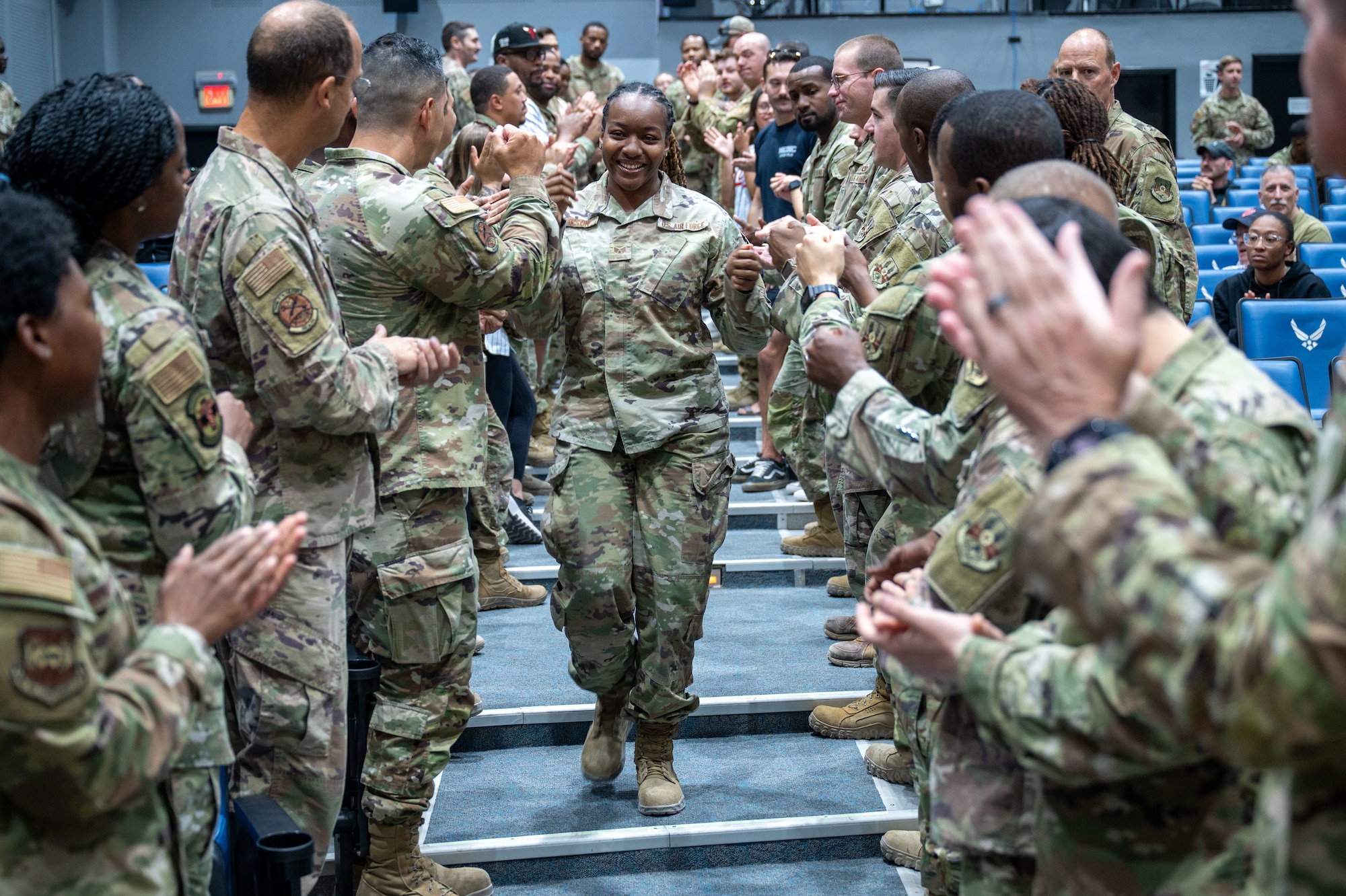 SSgt Frieson walks middle frame down an aisle with Airmen on either side of him with fist bumps, high-fives and handshakes