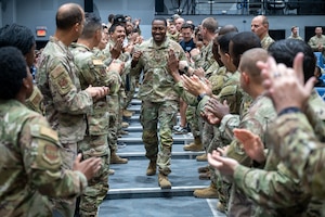 SSgt Lee walks middle frame down an aisle with Airmen on either side of him with fist bumps, high-fives and handshakes