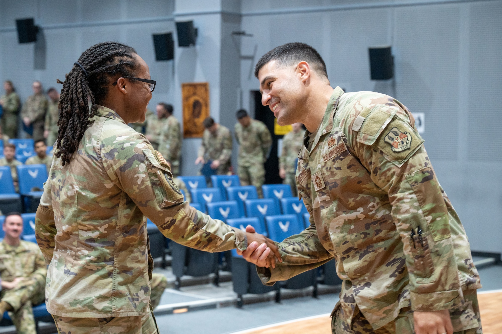 Chief Correa right of frame is shaking SSgt Thomas's hand on the left side of the frame with her back turned to camera and Chief Correa's profile view
