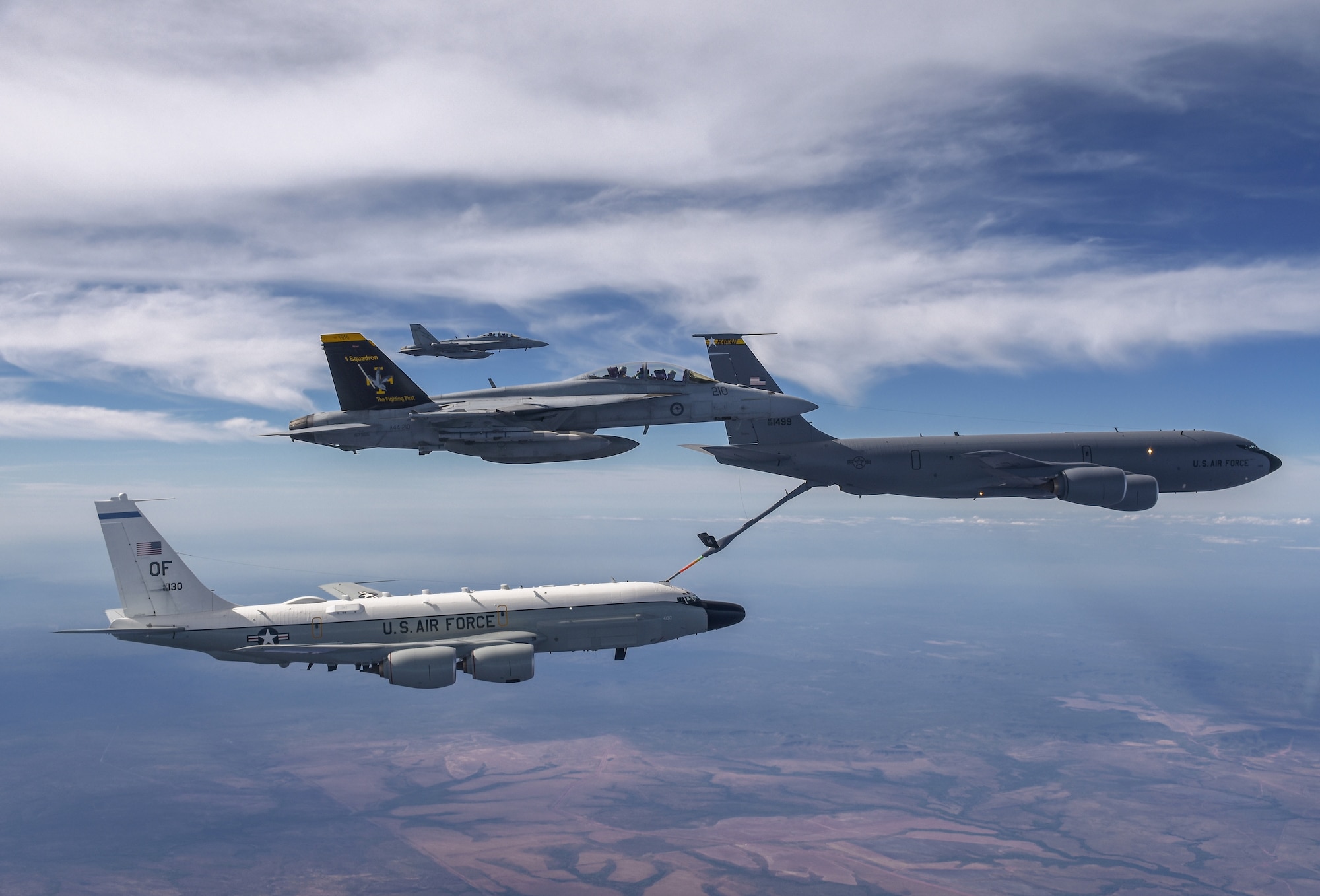 A Royal Australian Air Force F/A-18F Super Hornet and EA-18G Growler fly beside a United States Air Force KC-135 tanker as it refuels a RC-135W