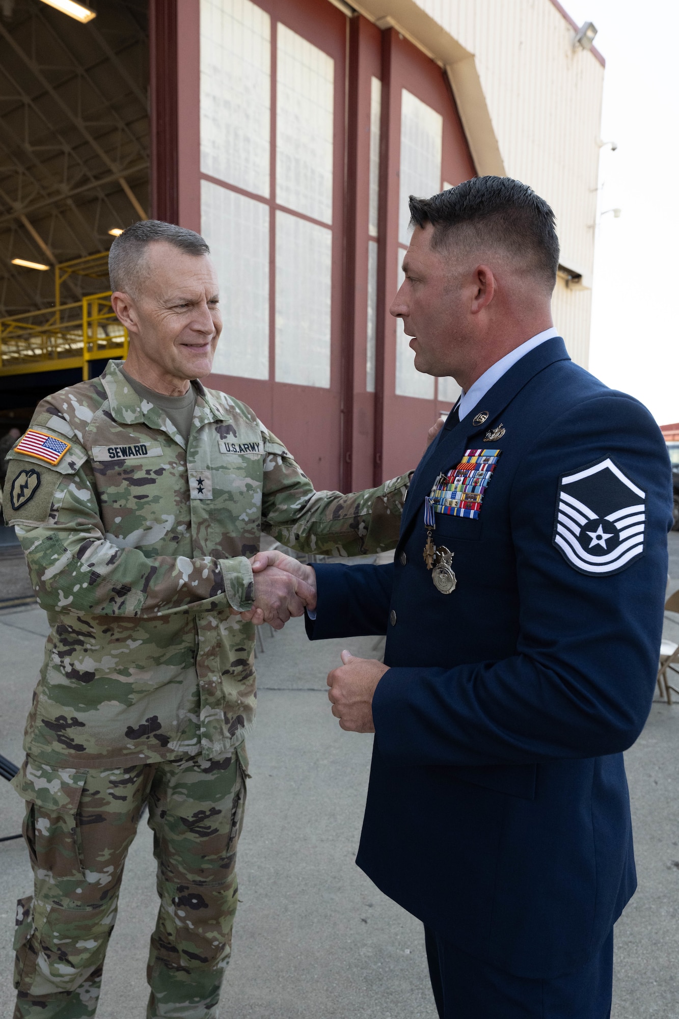 West Virginia National Guard Adjutant General Maj. Gen. Jim Seward, left, shakes hand with U.S. Air National Guard Master Sgt. Keith McGraw, right, Phoenix Raven, assigned to the 130th Airlift Wing, Charleston, West Virginia, Aug. 3, 2025. McGraw was awarded the DFC for his distinctive heroism and extraordinary achievement while participating in aerial flight on August 30, 2021 in and over Kabul, Afghanistan in support of Operation Allies Refuge. Operation Allies Refuge was the largest non-combatant evacuation operation in American history where more than 120,000 Afghan citizens were assisted by Airmen. (U.S. Air National Guard photo by Staff Sgt. Alancea Grant)