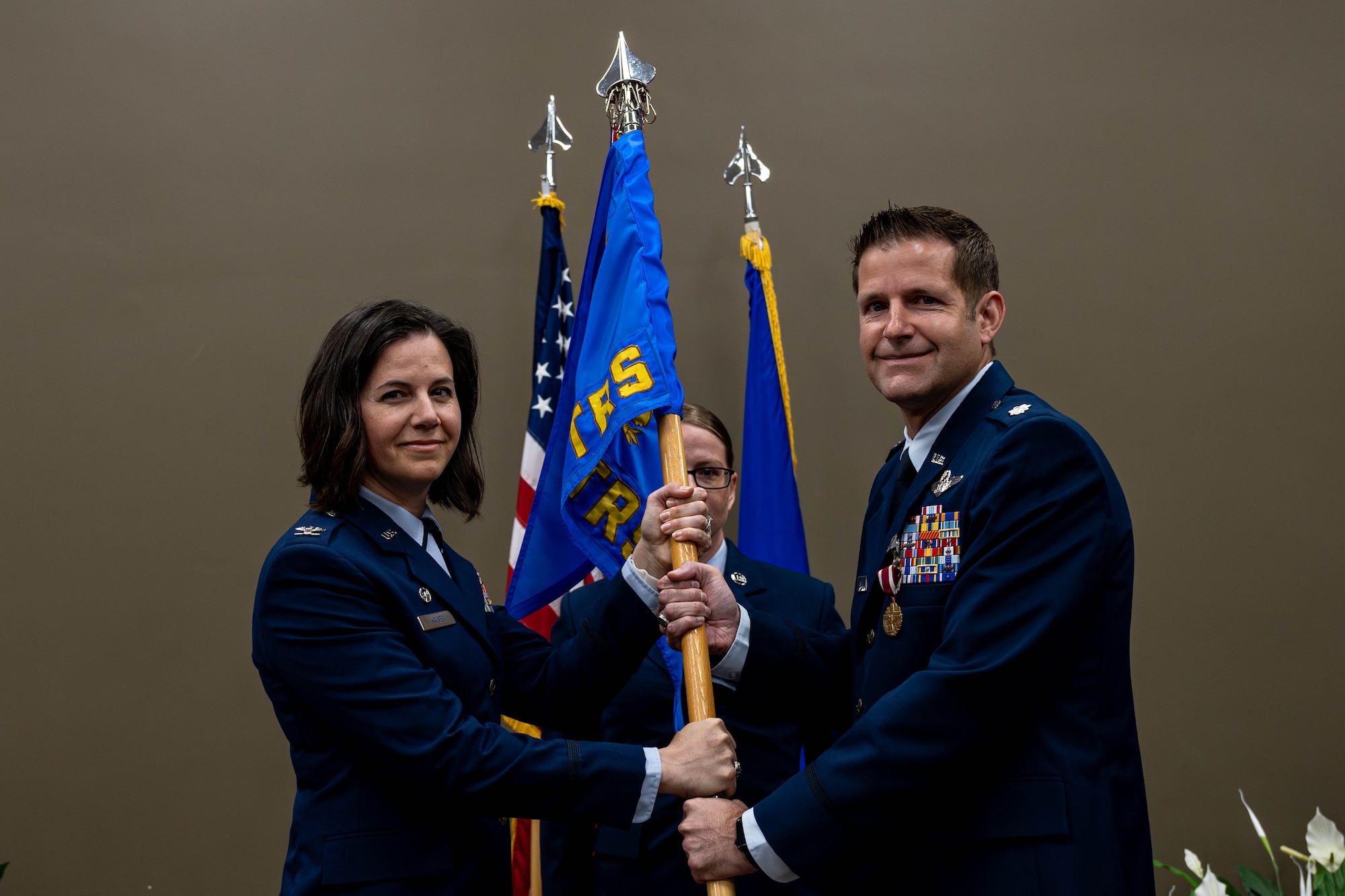 Col. Sarah Kaiser, U.S. Air Force Expeditionary Operations School commandant, left, and Lt. Col. Zachary Unger, 435th Training Squadron outgoing commander, pass the guidon during the 435th TRS Change of Command on Scott Air Force Base, Illinois, May 28, 2025. The 435th TRS provides critical support in air mobility, education, and full-spectrum command and control instruction, with a continued emphasis on improving operational tactics, techniques, and procedures. (U.S. Air Force photo by Senior Airman Violette Hosack)