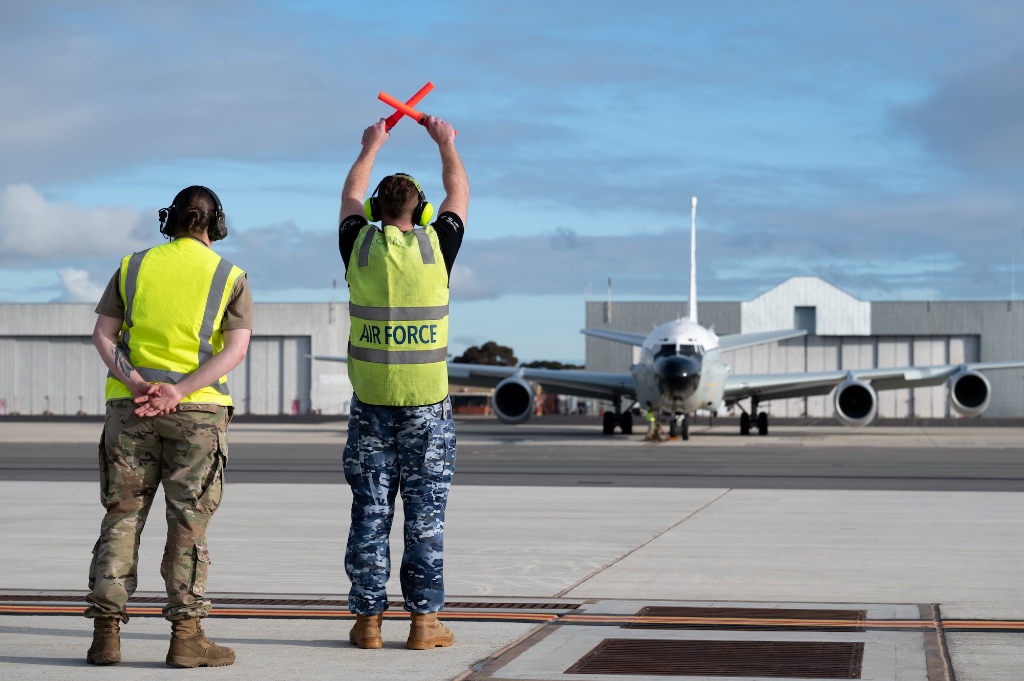 A RAAF member and USAF member signals to an RC-135V/W Rivet Joint pilot