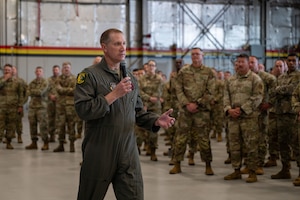 Wing commander gestures while speaking to a group of Airmen