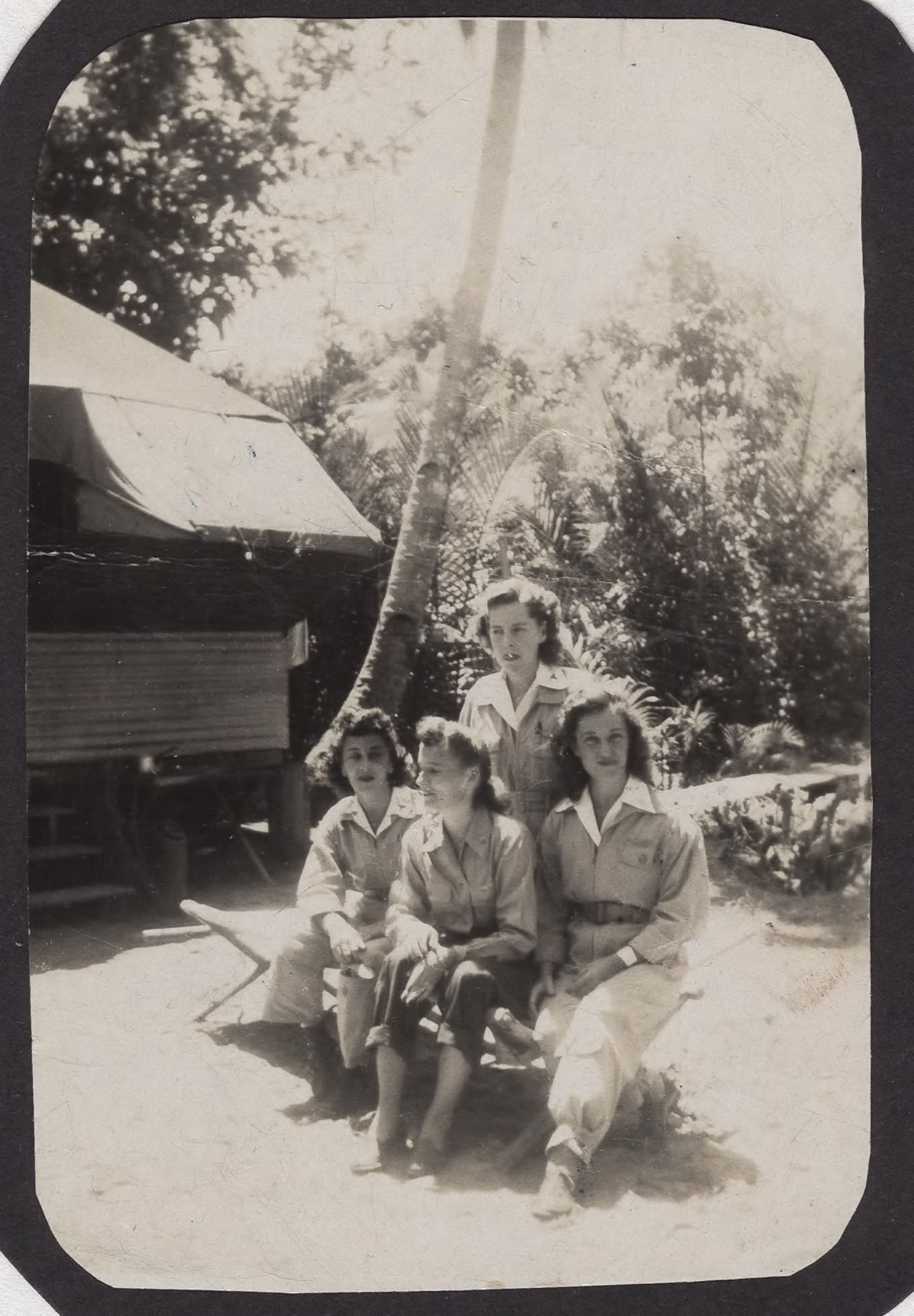 three flight nurses sitting on a bench outside with a 4th nurse standing behind them.