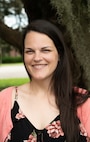 A Caucasian woman poses for a portrait photo in front of a tree on a sunny day in Charleston, South Carolina.