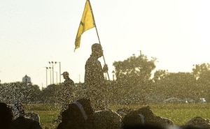 A silhouette of a man carries a yellow flag at sunrise.