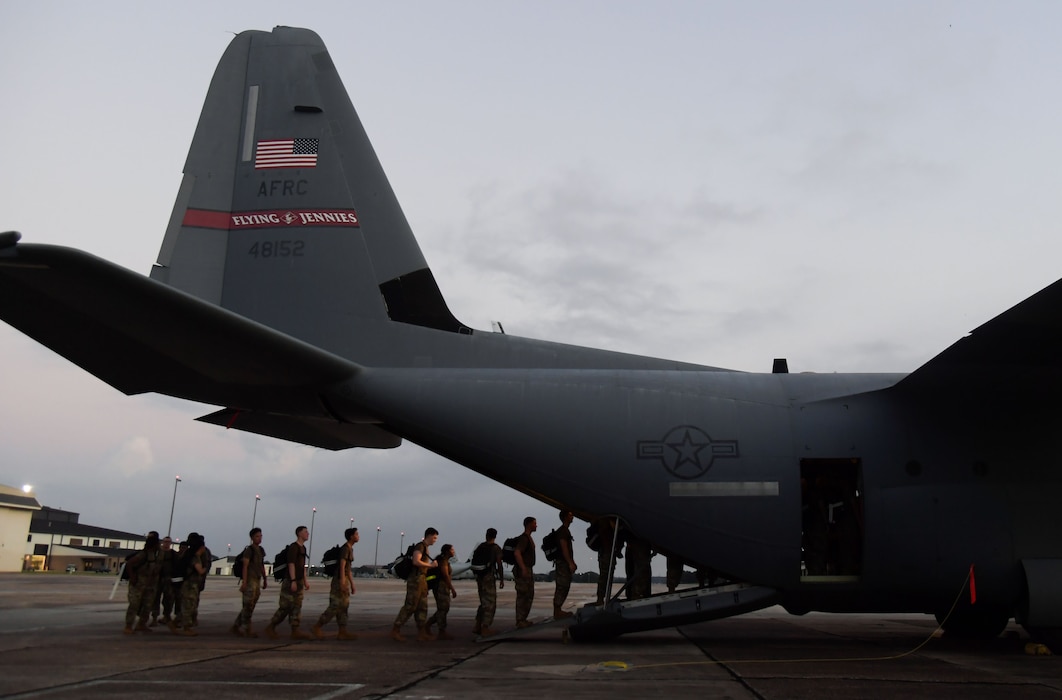 A Group of people board the back of a C-130 aircraft