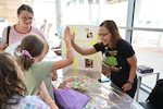 Juliana Luciano, CRDAMC infection prevention branch manager, gives a high five to a young attendee after completing a hand hygiene demonstration during Kidz Fest, Aug. 2. The station taught children proper handwashing techniques to help prevent the spread of disease.