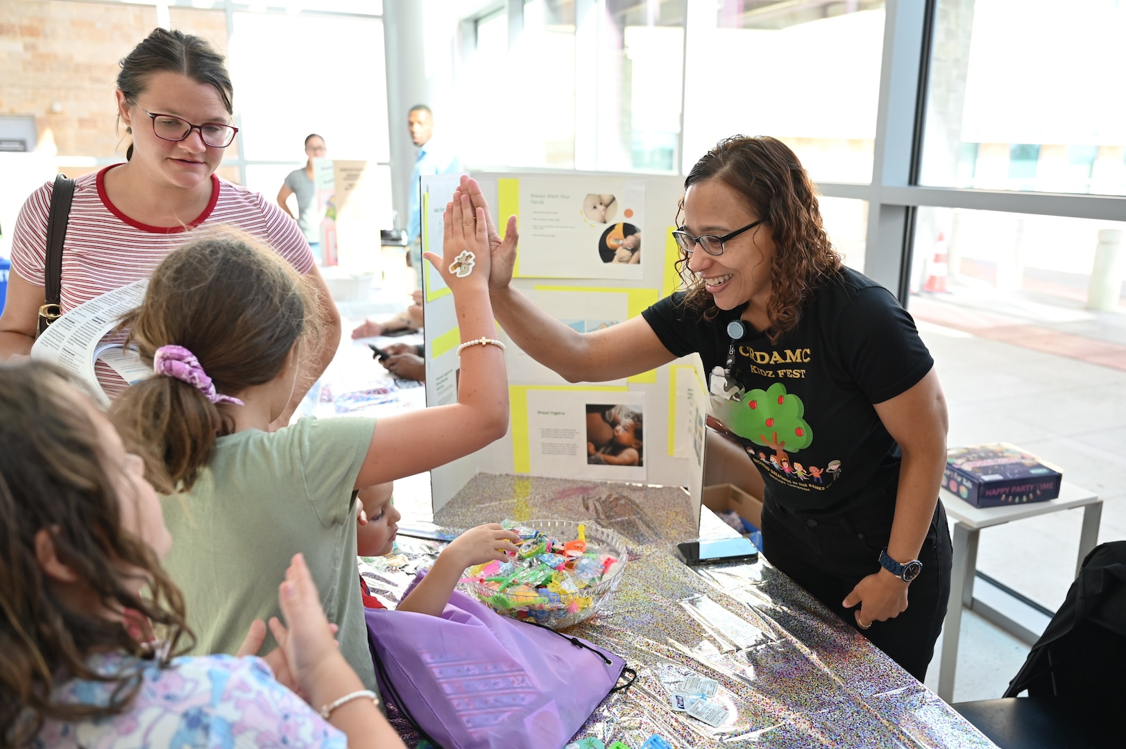 Juliana Luciano, CRDAMC infection prevention branch manager, gives a high five to a young attendee after completing a hand hygiene demonstration during Kidz Fest, Aug. 2. The station taught children proper handwashing techniques to help prevent the spread of disease.