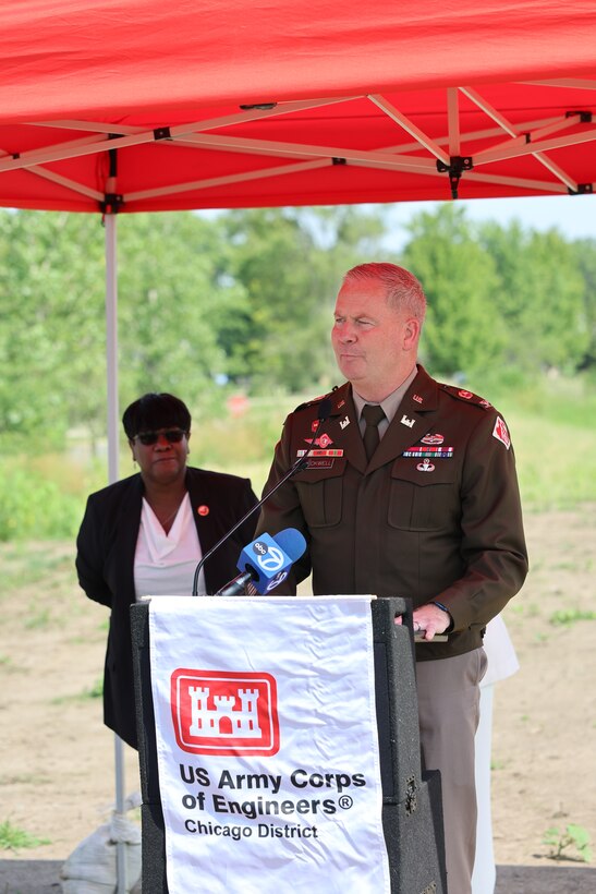 Commander stands behind U.S. Army Corps of Engineers podium with women behind him in the distance.