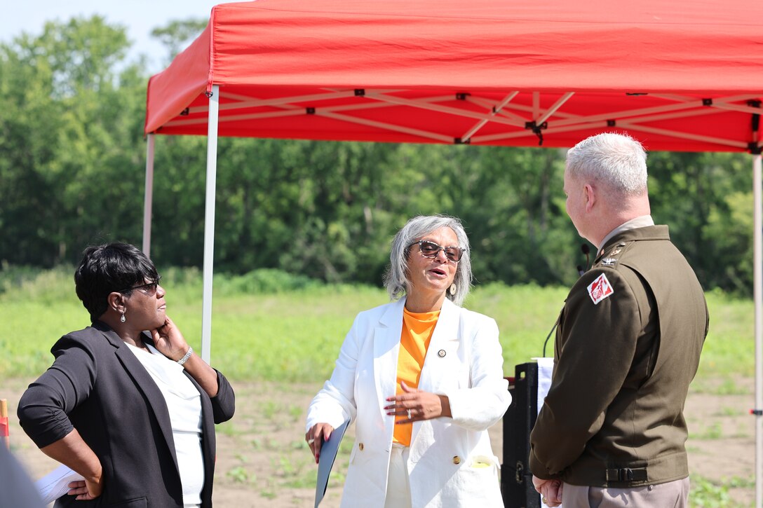 Group of three people chatting with red canopy behind them.