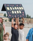 Two children hold up a sign saying "Welcome Home."