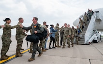 Airmen greet other Airmen as they step off an aircraft.