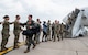Airmen greet other Airmen as they step off an aircraft.